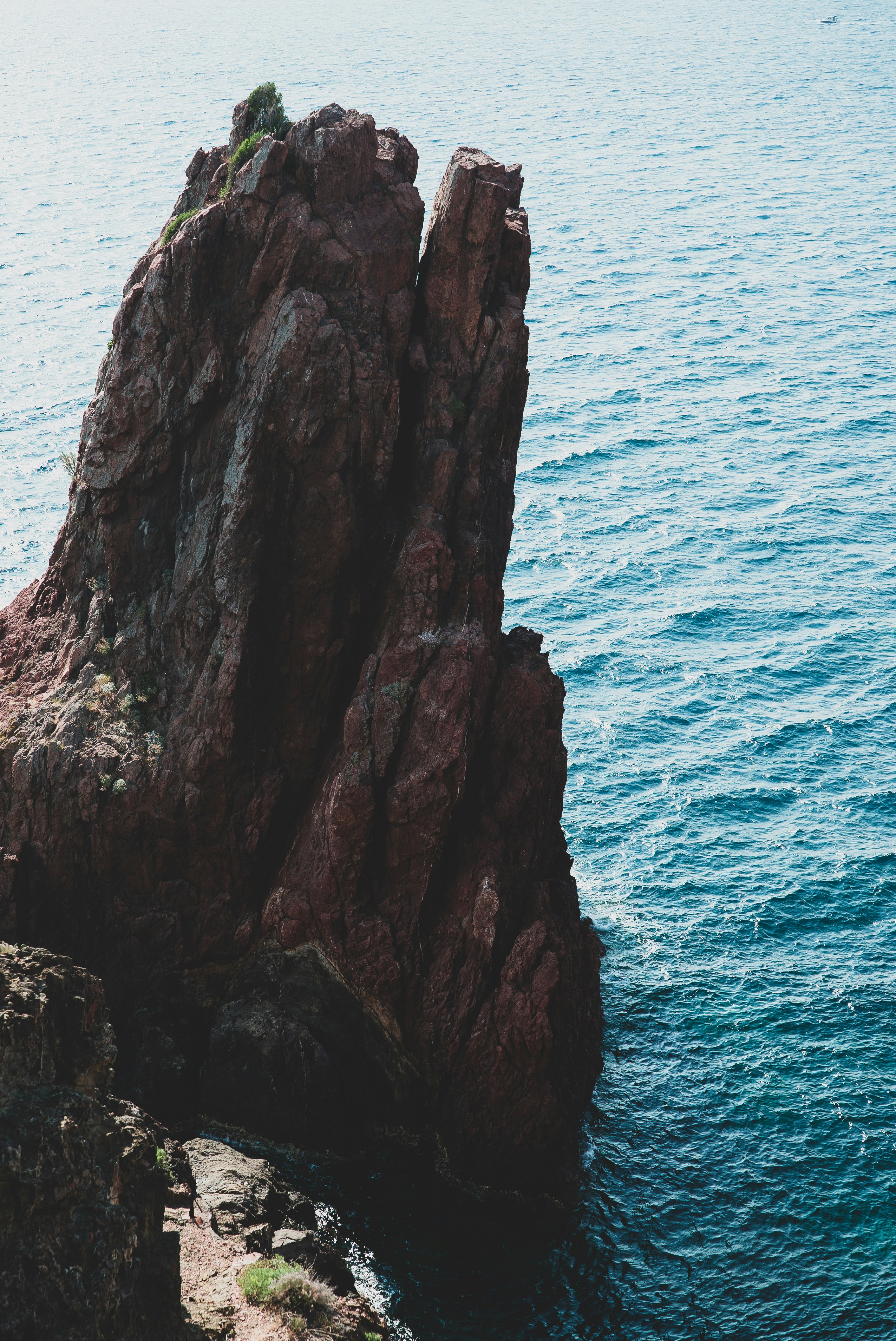 black and brown rock formation beside body of water at daytime